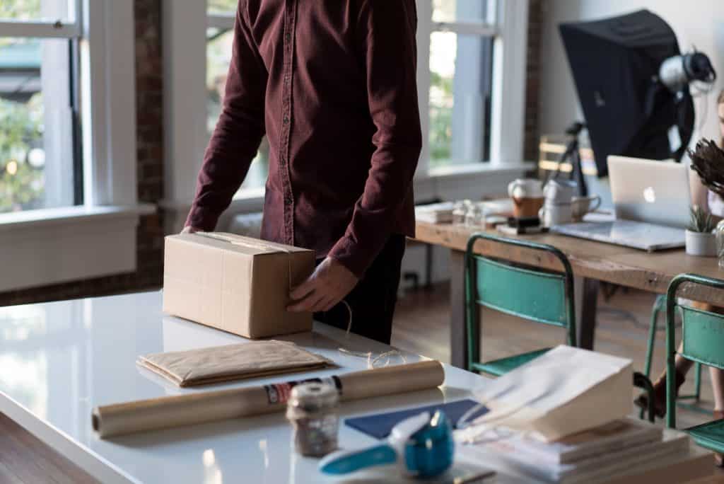 Person packaging a box in a workspace.
