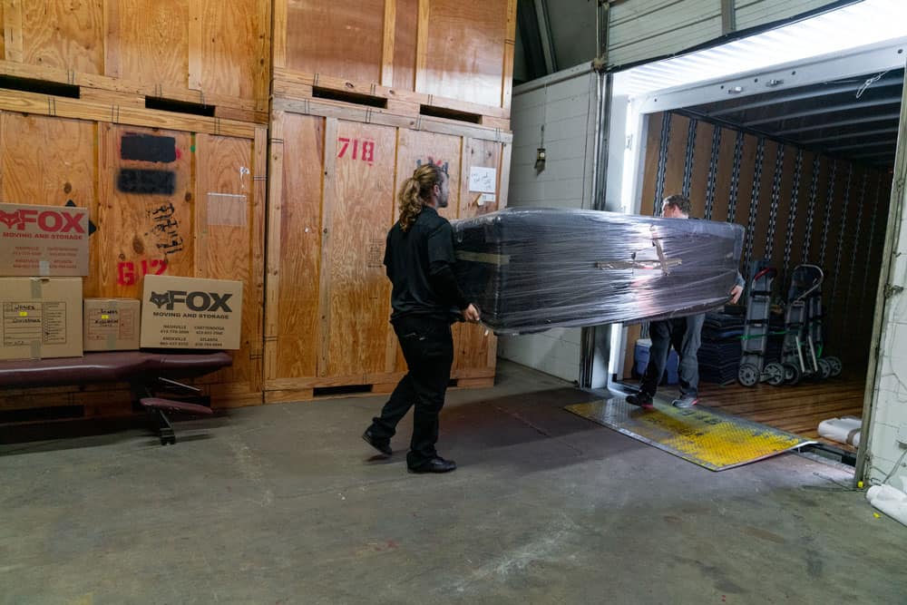 large sofe is being unloaded from a moving truck to the storage facility