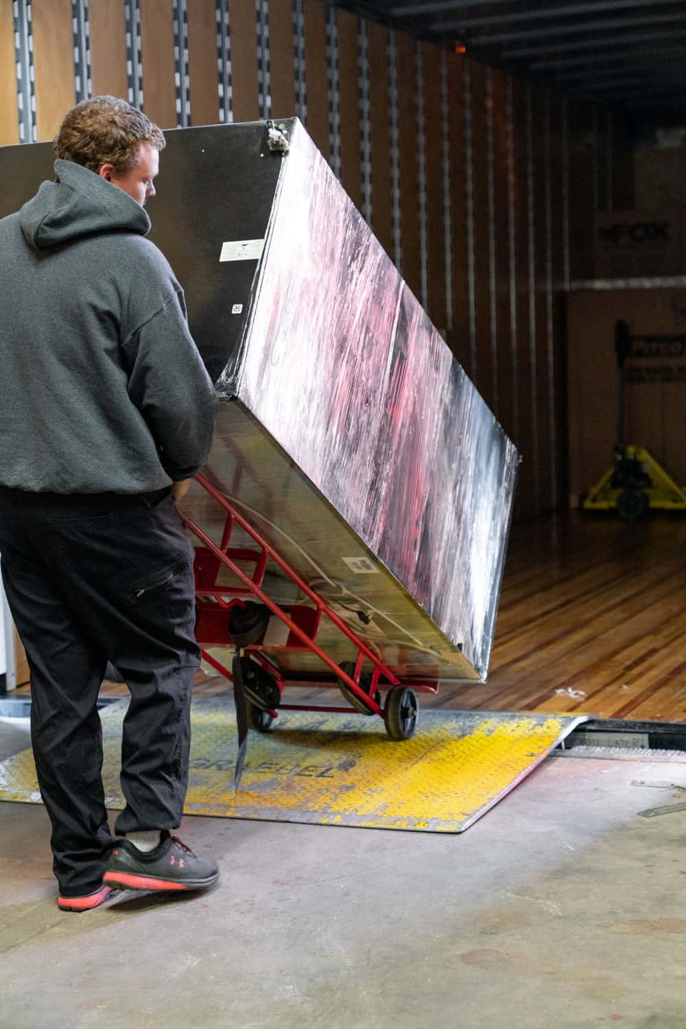 a single mover moving a large residential item from a moving truck into the storage facility with a dolly