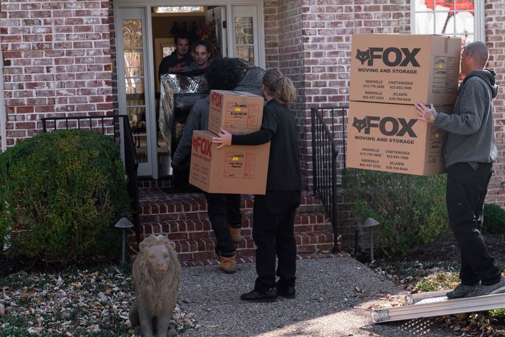 5 movers of fox moving and storage holding sofa and boxes moving in the apartment