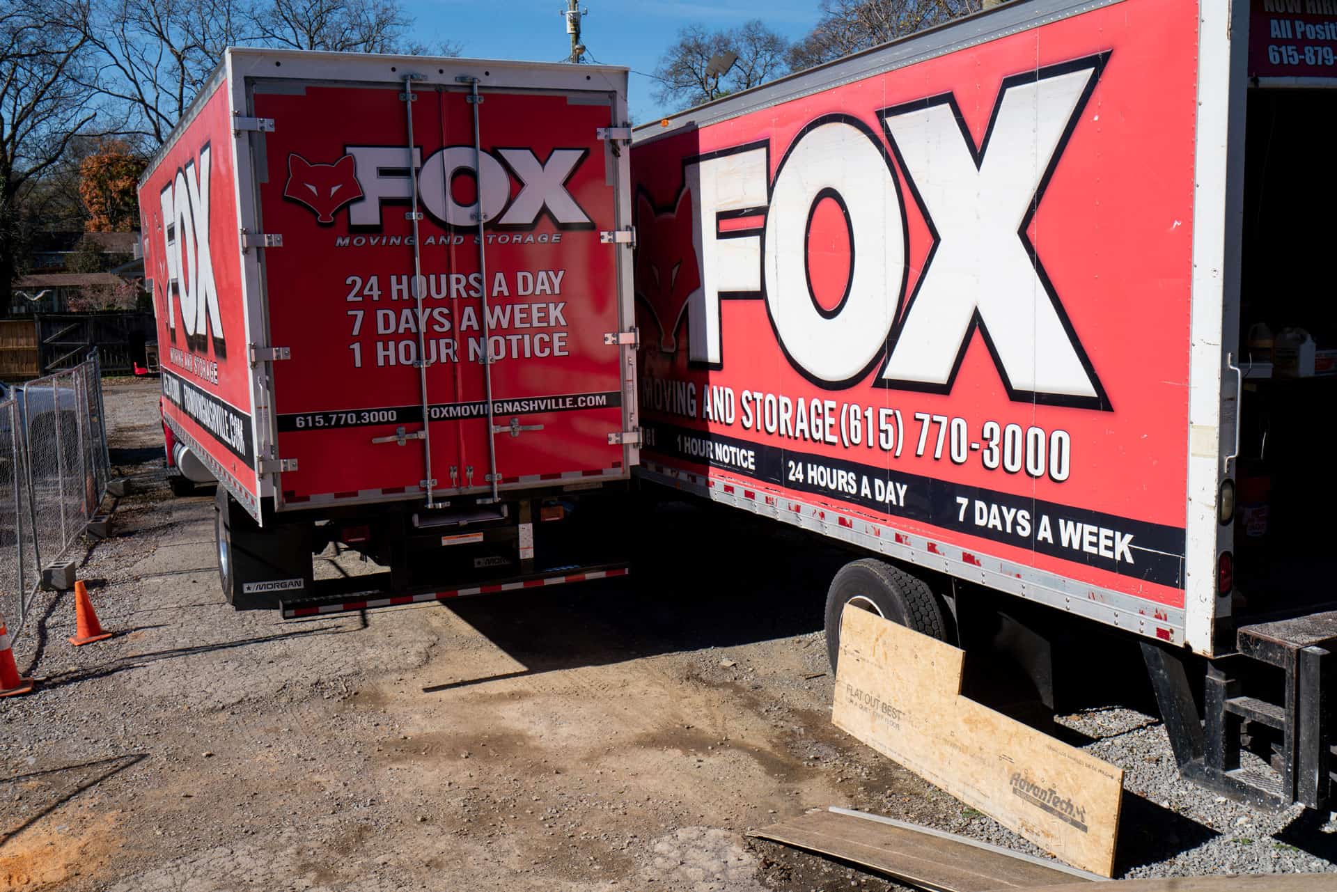 two red moving trucks of fox moving and storage, standing side by side in a tight space